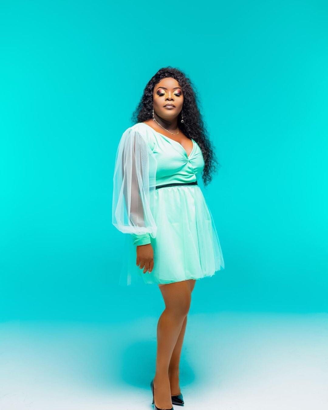 Lourena Nhate usando vestido cor de menta em foto de estudio com fundo azul