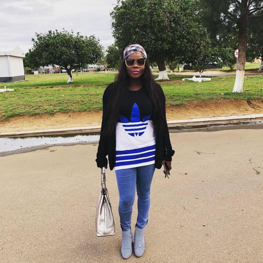 Lourena Nhate usando vestido azul com estampa branca e camisola preta